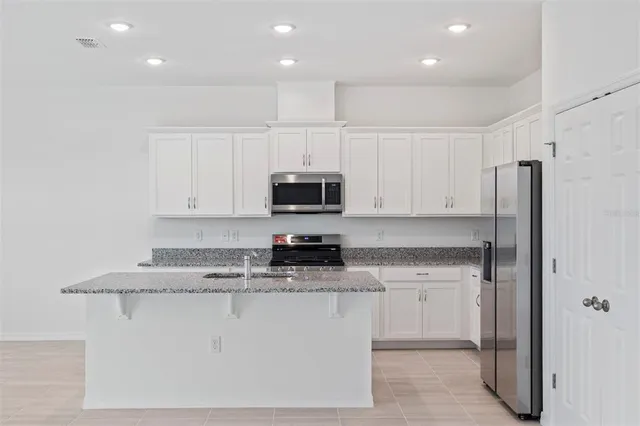 a kitchen with stainless steel appliances granite countertop a stove a sink and a refrigerator