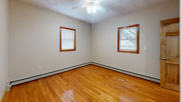 a view of an empty room with a window and wooden floor