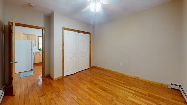 an empty room with wooden floor cabinet and windows