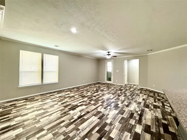 a view of a big room with wooden floor and windows