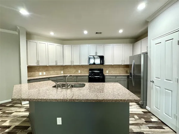 a kitchen with granite countertop a refrigerator and a stove top oven