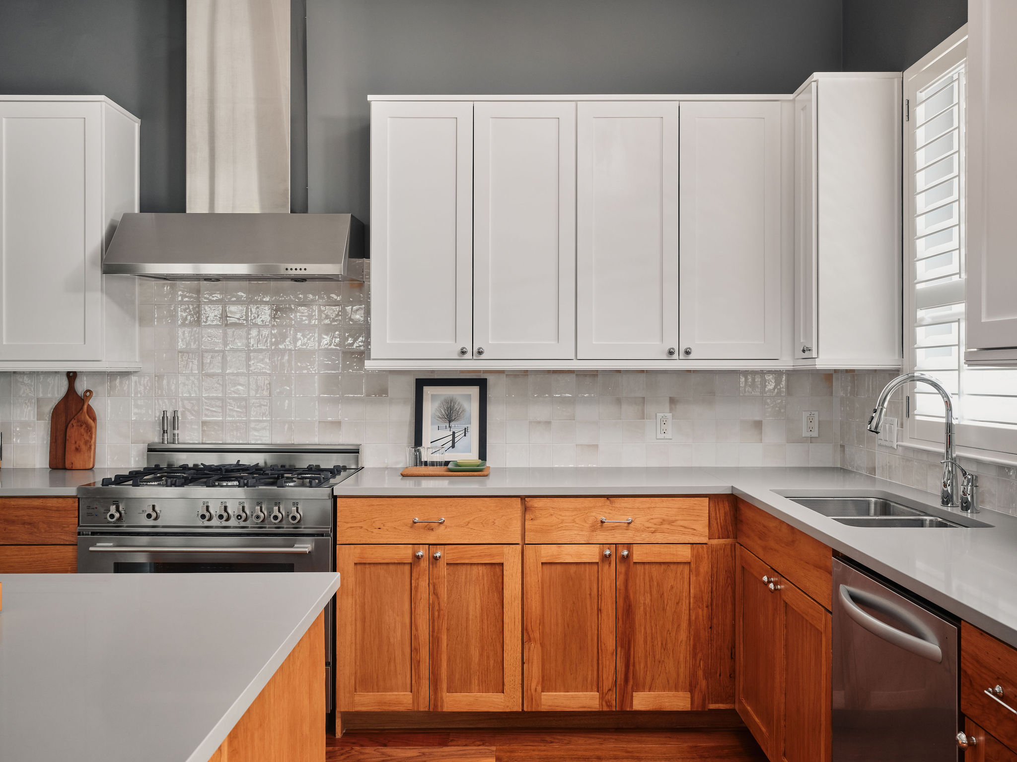 1504 Collier Street, Unit 4 Austin, TX 78704 - Photo 12 of 38 Two tone kitchen with stainless steel appliances, backsplash, wood finished floors, and two tone cabinets