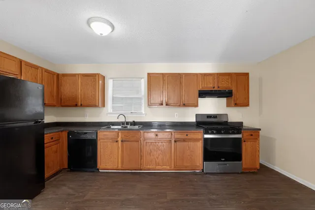 a kitchen with stainless steel appliances granite countertop a stove top oven a sink dishwasher and a refrigerator