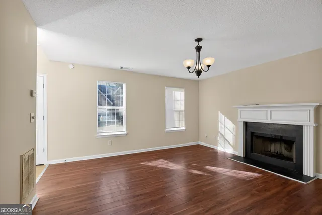 a view of an empty room with wooden floor fireplace and a window