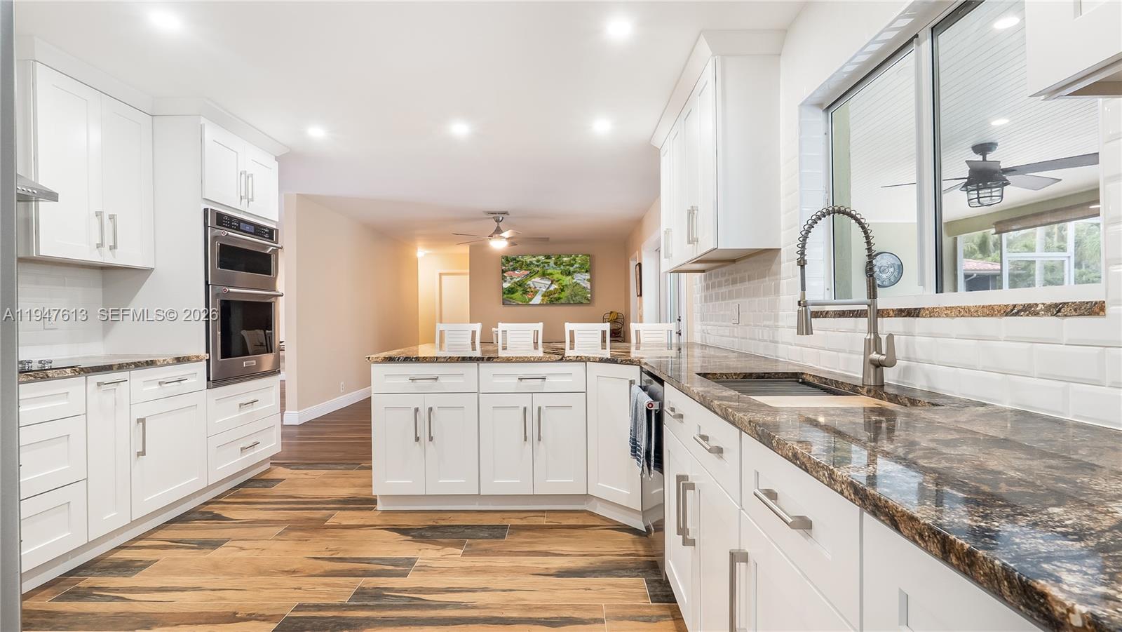 11071 Southwest 30th Court Davie, FL 33328 - Photo 6 of 44 a large kitchen with granite countertop a white stove top oven and white cabinets