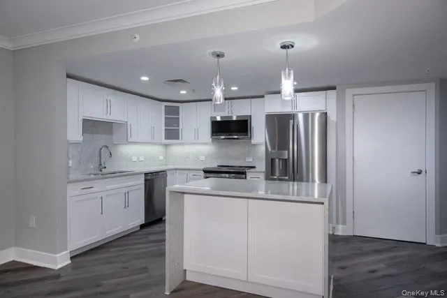 a kitchen with stainless steel appliances granite countertop a refrigerator a sink dishwasher a stove and white cabinets with wooden floor