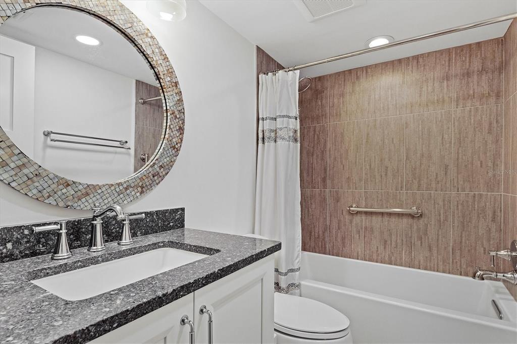 5740 Midnight Pass Road, Unit 303F Sarasota, FL 34242 - Photo 28 of 51 a bathroom with a granite countertop bathtub sink vanity mirror and toilet
