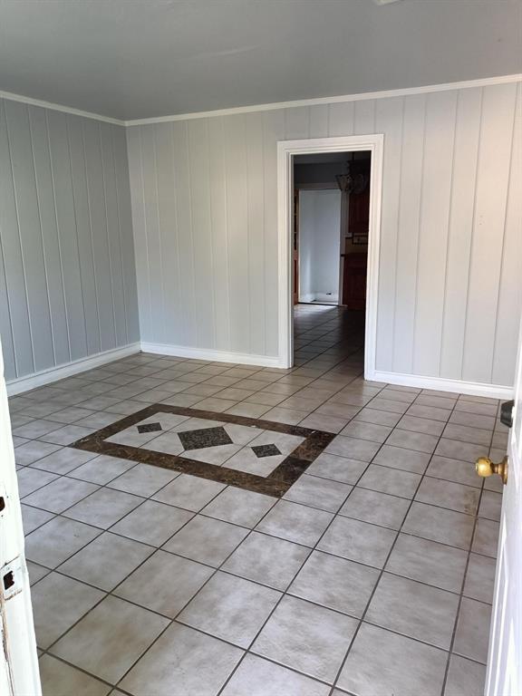3213 8th Avenue Fort Worth, TX 76110 - Photo 4 of 15 featuring light tile patterned flooring, crown molding, and wooden walls