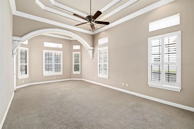 an empty room with windows and ceiling fan