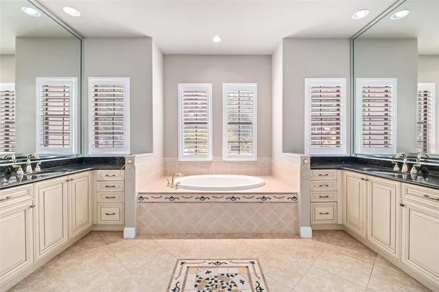 a spacious bathroom with a granite countertop tub a sink and a large window