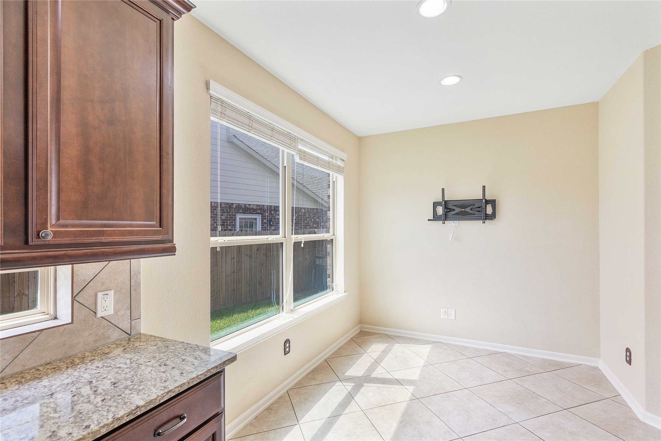 17206 Upper Ridge Lane Humble, TX 77346 - Photo 9 of 50 Bright and inviting breakfast nook with large windows, tile flooring, and adjacent to a kitchen area with granite countertops and dark wood cabinetry. Ideal for casual dining and enjoying natural light.