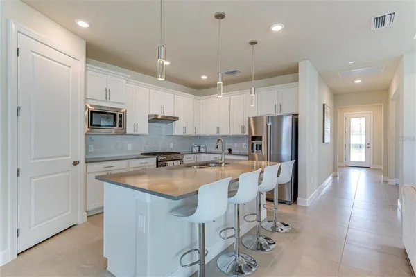 a large living room with stainless steel appliances kitchen island granite countertop a couch and a flat screen tv