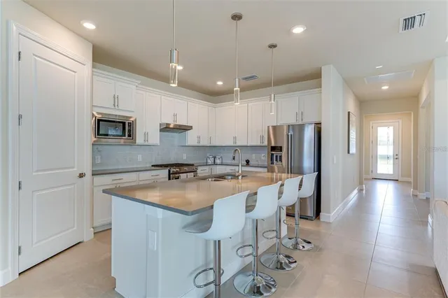 a large living room with stainless steel appliances kitchen island granite countertop a couch and a flat screen tv