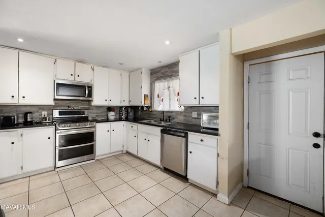 a kitchen with granite countertop white cabinets and stainless steel appliances