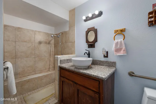 a bathroom with a granite countertop sink a mirror and shower