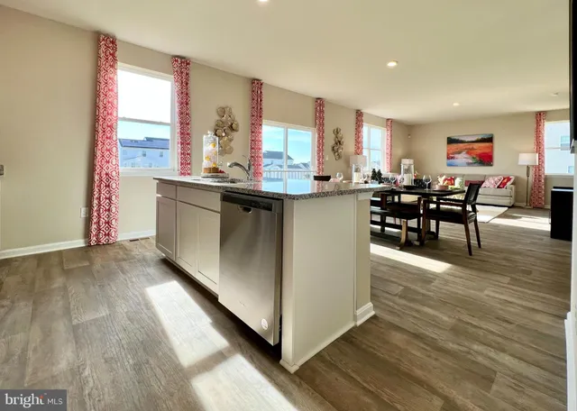 a living room with stainless steel appliances granite countertop furniture wooden floor and a window