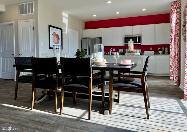 a view of kitchen with stainless steel appliances granite countertop dining table chairs cabinets and wooden floor