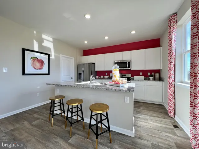 a kitchen with stainless steel appliances granite countertop a dining table chairs and wooden floor