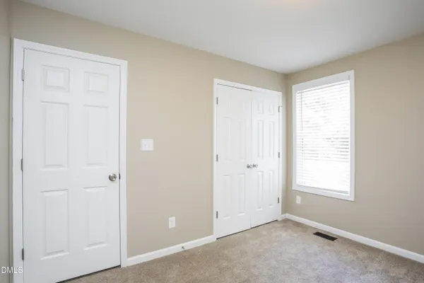 a view of an empty room with closet and a window