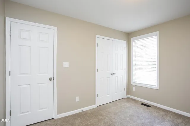 a view of an empty room with closet and a window