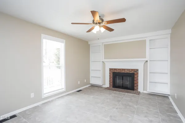 an empty room with fireplace and fan