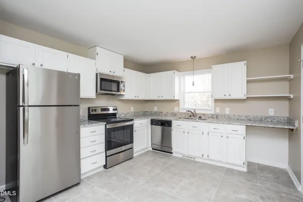 a kitchen with granite countertop a refrigerator stove top oven and sink