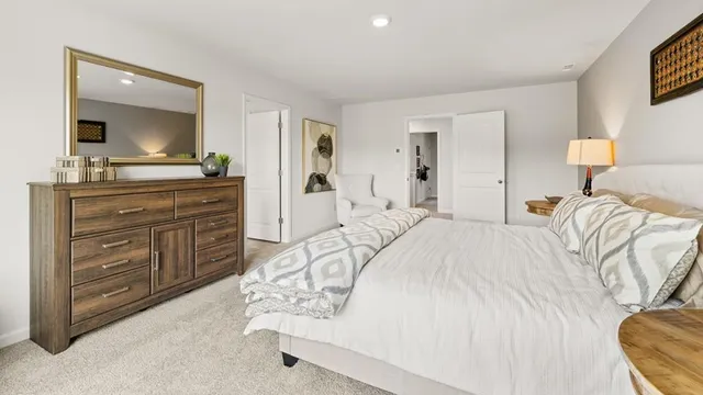 a spacious bedroom with a bed and a mirror on dresser