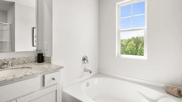 a bathroom with a granite countertop sink and a bathtub with a window