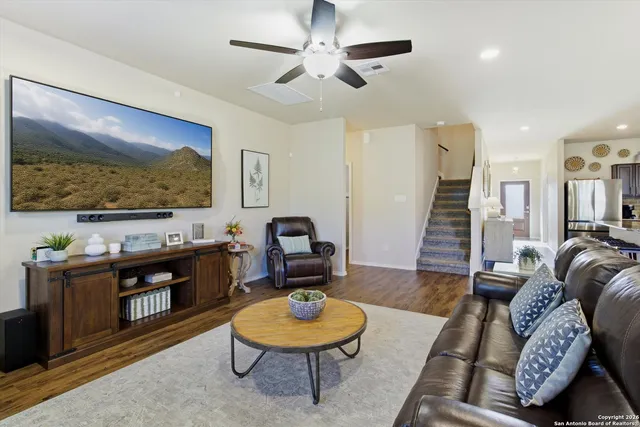 a kitchen with stainless steel appliances granite countertop a stove a sink a refrigerator and white cabinets with wooden floor