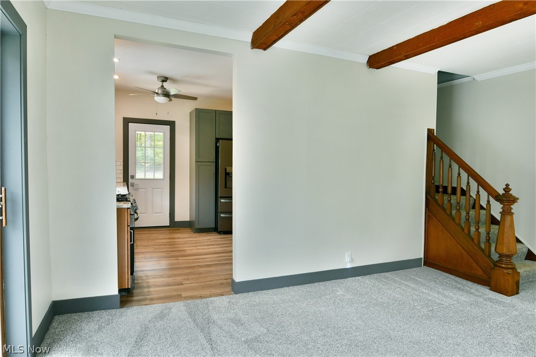892 Yankee Run Road Masury, OH 44438 - Photo 11 of 50 Expansive carpeted area with exposed ceiling beams and a wooden staircase
