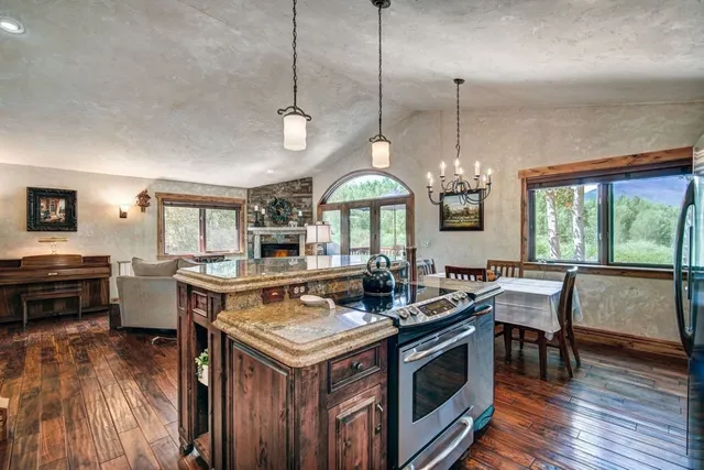 a kitchen with a stove a sink dishwasher a dining table and chairs with wooden floor