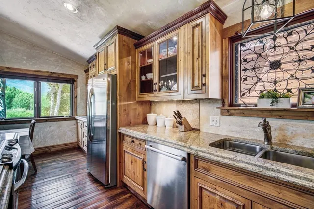 a kitchen with stainless steel appliances granite countertop a sink a stove and a wooden cabinets