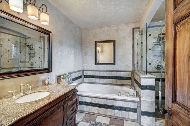 a bathroom with a granite countertop tub sink and mirror