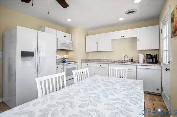 a kitchen with stainless steel appliances kitchen island granite countertop a refrigerator sink and white cabinets