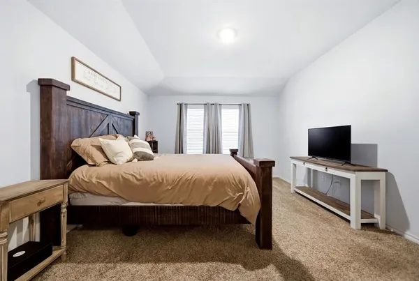 a spacious bedroom with a bed and a flat screen tv