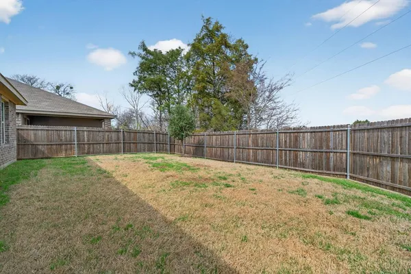 a view of a backyard with a fence and trees