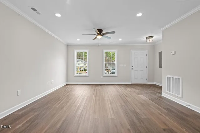 an empty room with wooden floor and windows