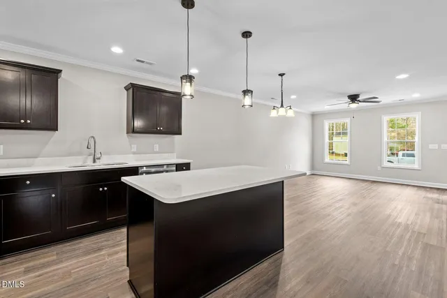 a kitchen with a center island wooden floor and a view of living room