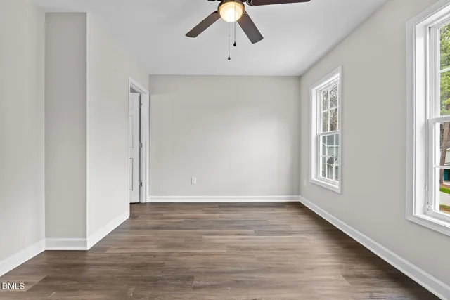 a view of an empty room with wooden floor and window