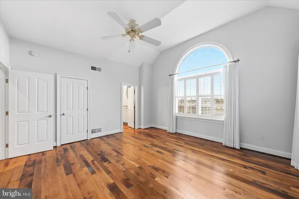 an empty room with wooden floor and fan