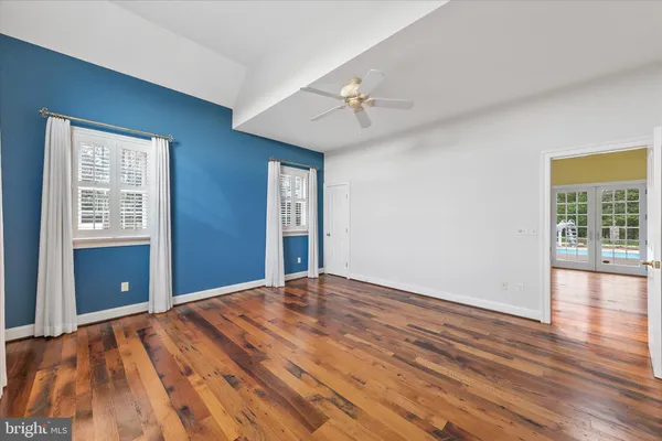 a view of empty room with wooden floor and fan