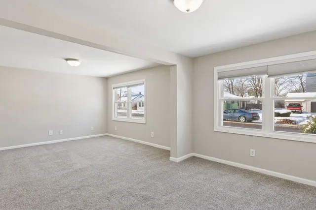 an empty room with windows and painting on the wall