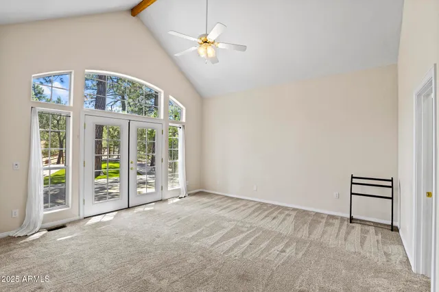 an empty room with windows and ceiling fan