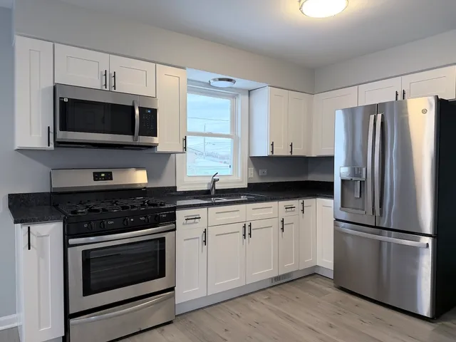 a kitchen with granite countertop a refrigerator stove and microwave