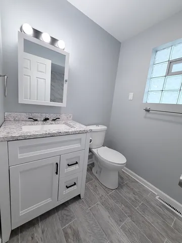 a bathroom with a granite countertop toilet sink and mirror