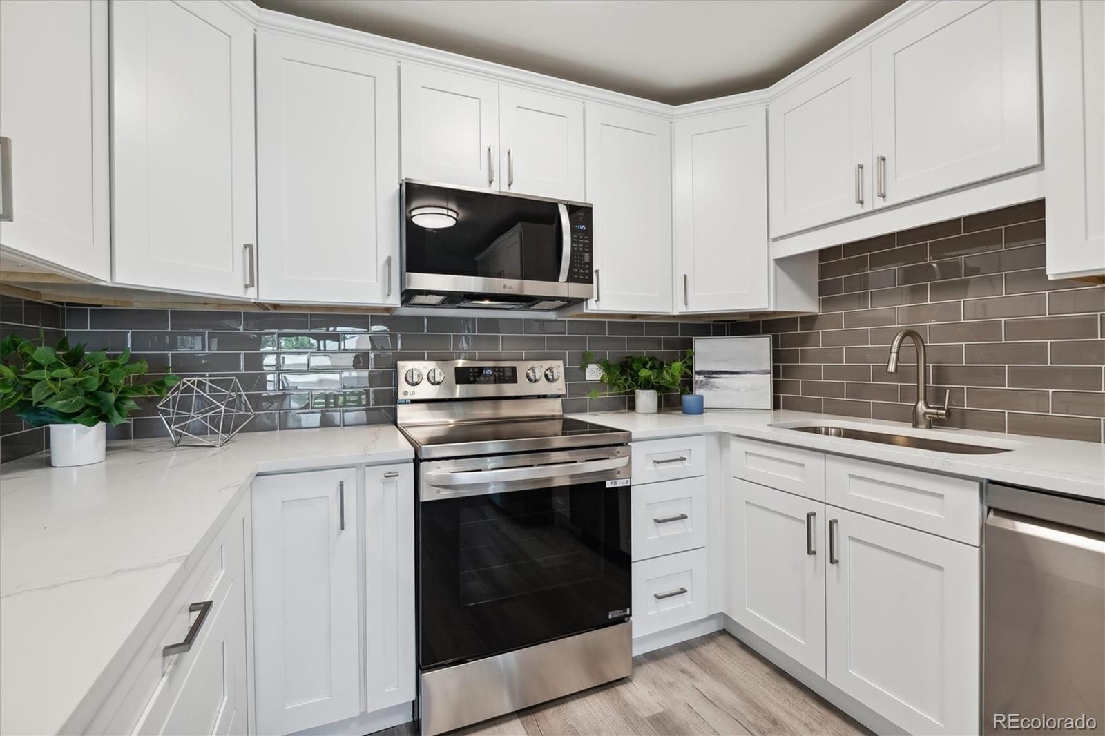 715 South Alton Way, Unit 5A Denver, CO 80247 - Photo 6 of 50 a kitchen with white cabinets stainless steel appliances and a sink