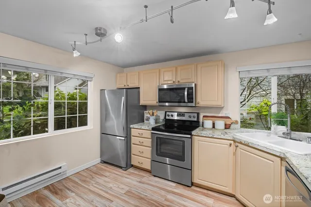 a kitchen with granite countertop a refrigerator oven a sink and dishwasher with wooden floor