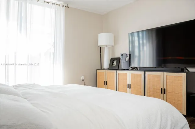 a bedroom with a large bed and a flat tv screen on dresser