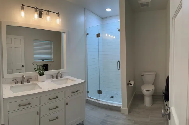 a bathroom with a double vanity sink toilet and shower