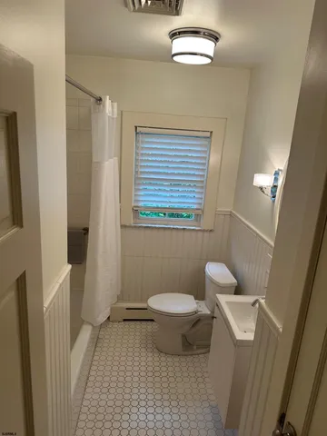 a bathroom with a toilet a sink a shower curtain and a window